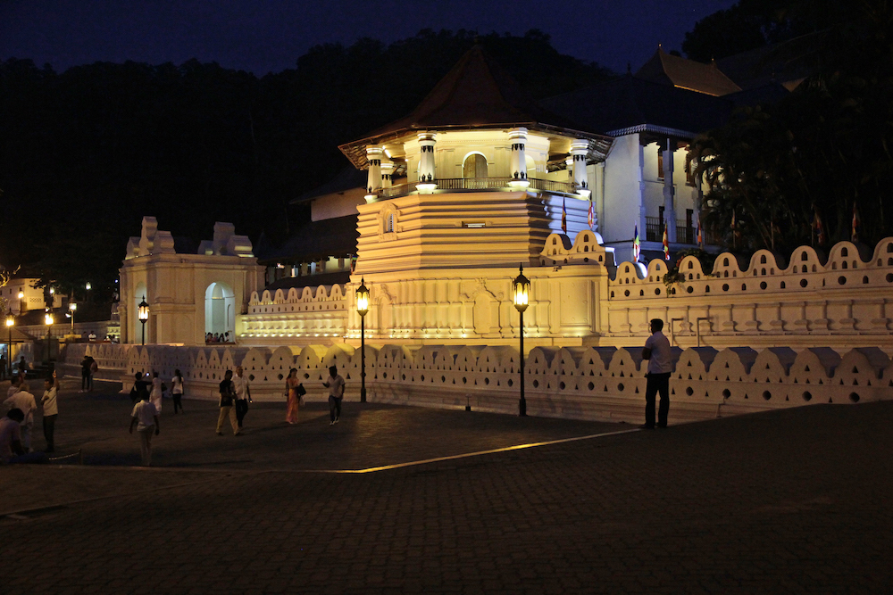 En bild på tandtemplet Sri Dalada Maligawa i staden Kandy. Det är natt och templet är upplyst.