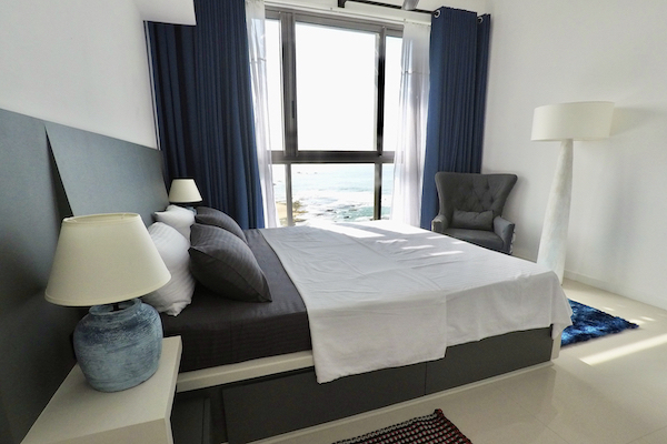 A picture of the apartment's bedroom with a sea view through the window.