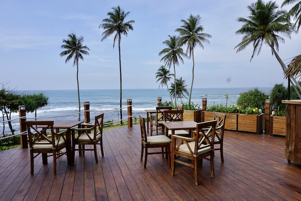 A picture of chairs and tables overlooking a tropical beach and ocean.