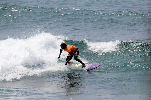 A picture of a surfer surfing a small wave with the ocean as a background.