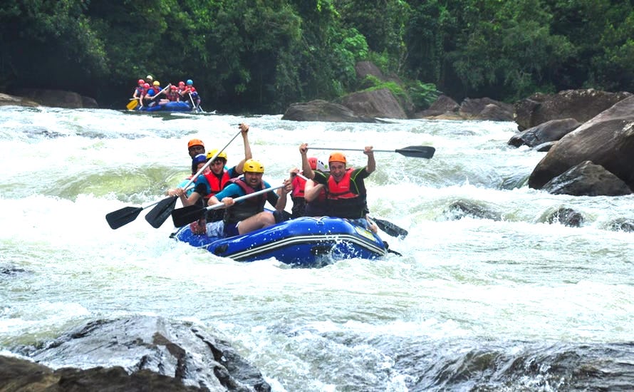 A picture of two full inflatable boats in a rapids in Kitulgala. Rocks and forest in the background.