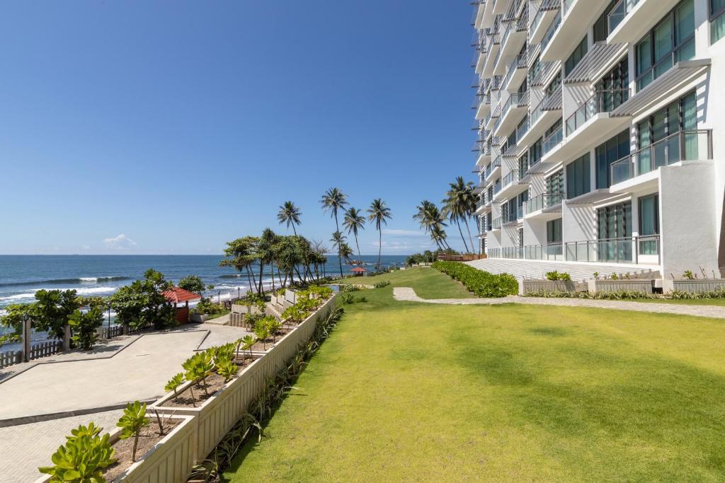 A picture of an apartment hotel, called Oceanfront Condos. The picture shows the ground floor and the garden with the sea as a background.