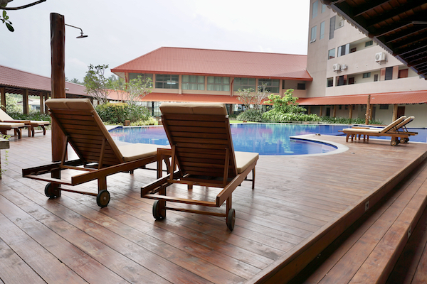 A picture of a swimming pool with sunbeds on a wooden deck.