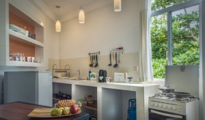 A picture of a kitchen with stove, kitchen table and window section in the apartment.