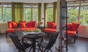 A picture of the top apartment's living room with table, chairs, sofas and window area.